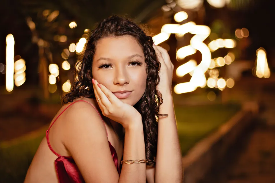 Woman resting her face on her hand with blurred lights behind her
