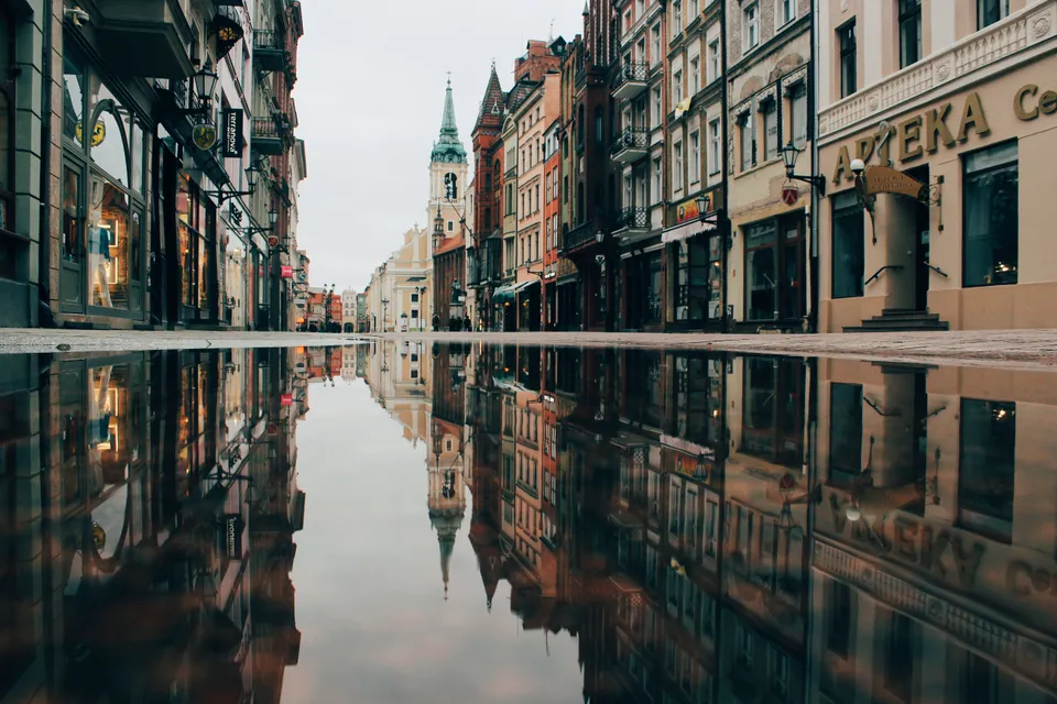 Historic street buildings reflected in a puddle