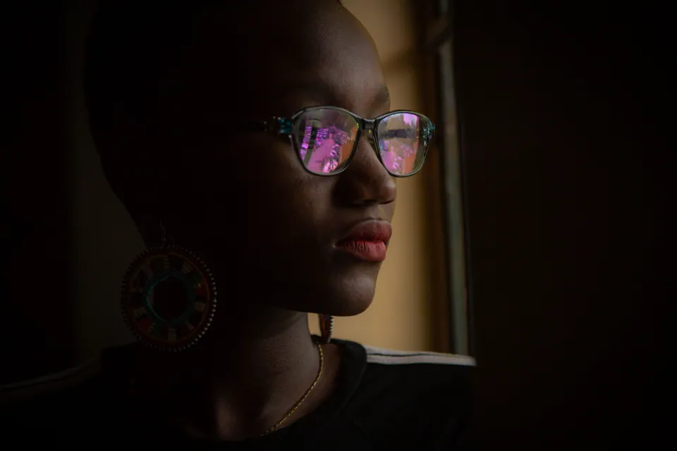 Side-lit portrait of a woman with reflections in her glasses