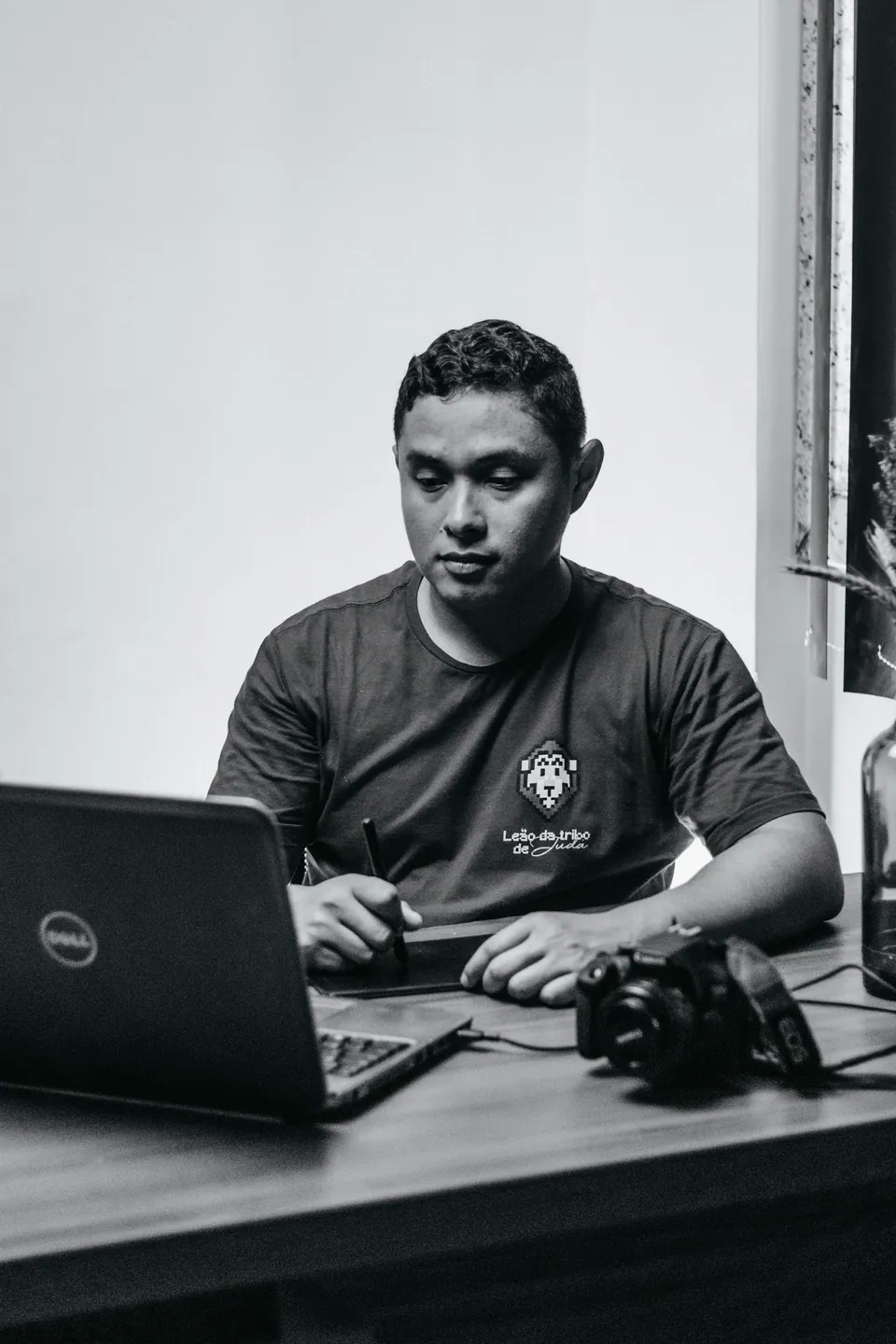 Photographer working beside a laptop, drawing tablet, and camera