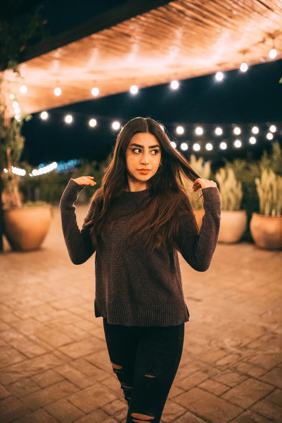 Woman standing beneath string lights at night
