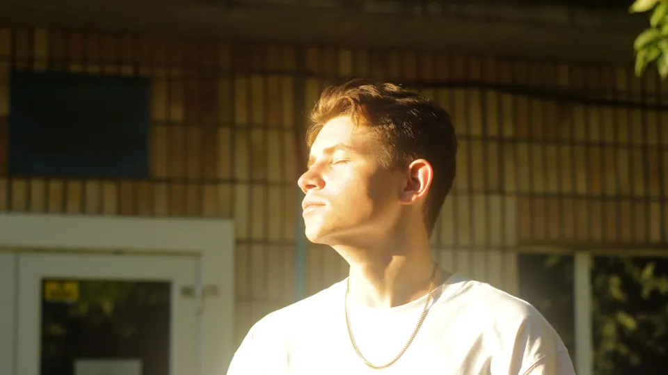 Man in a white shirt with bright sunlight across his face
