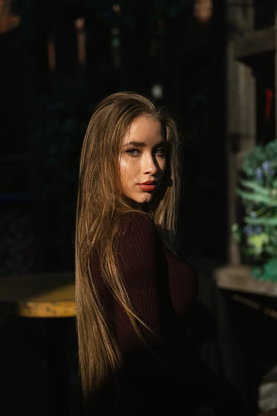 Woman standing in sunlight against a darker outdoor background