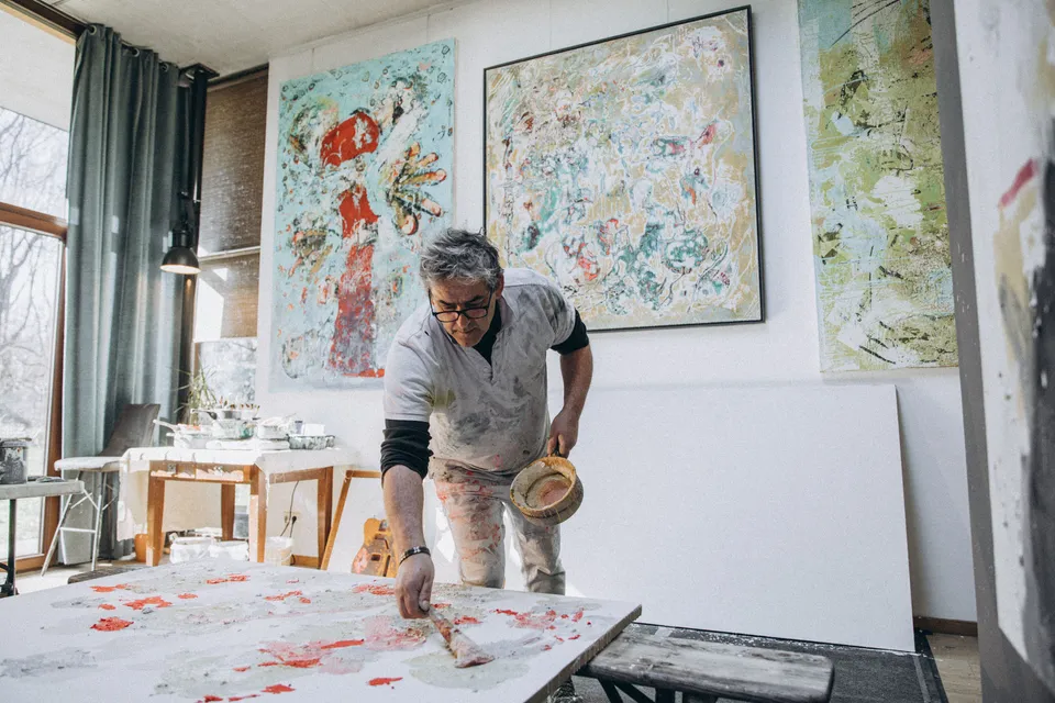 Artist working on a large abstract canvas in a studio