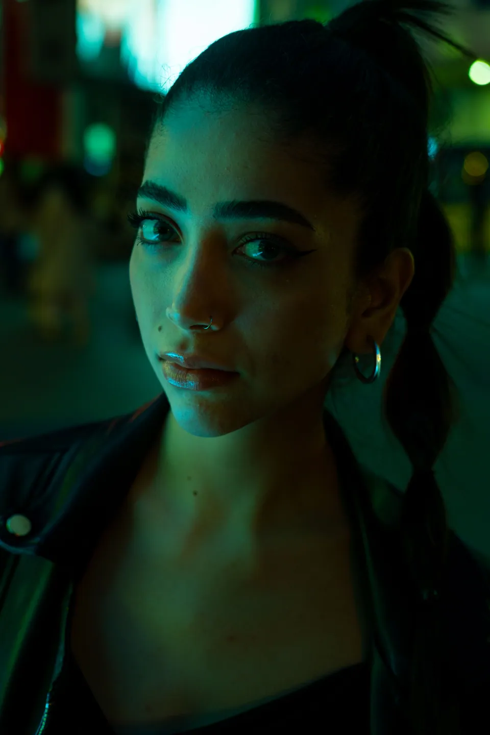 Portrait of a woman illuminated by green and blue light at night