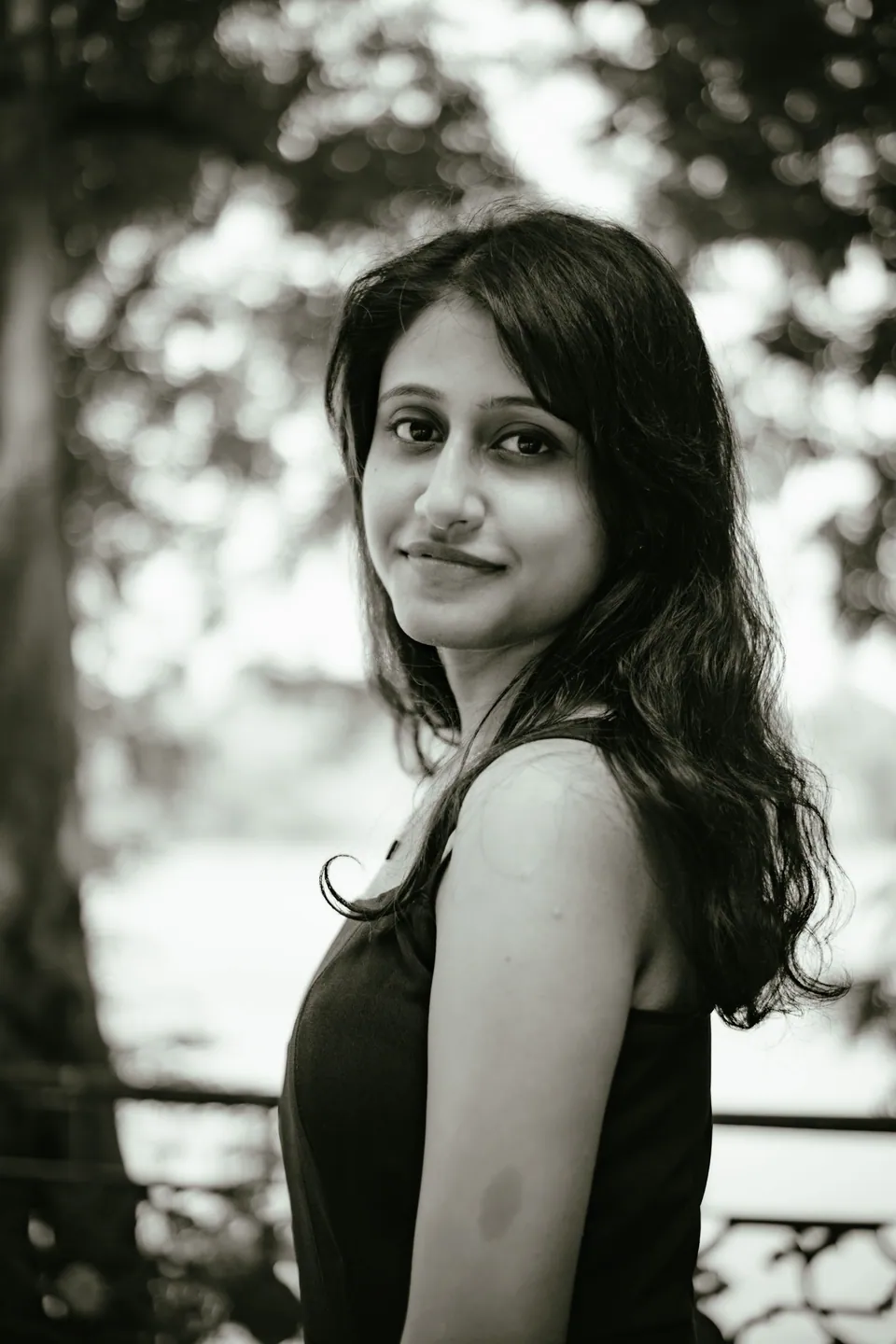 Black-and-white outdoor portrait with softly blurred foliage