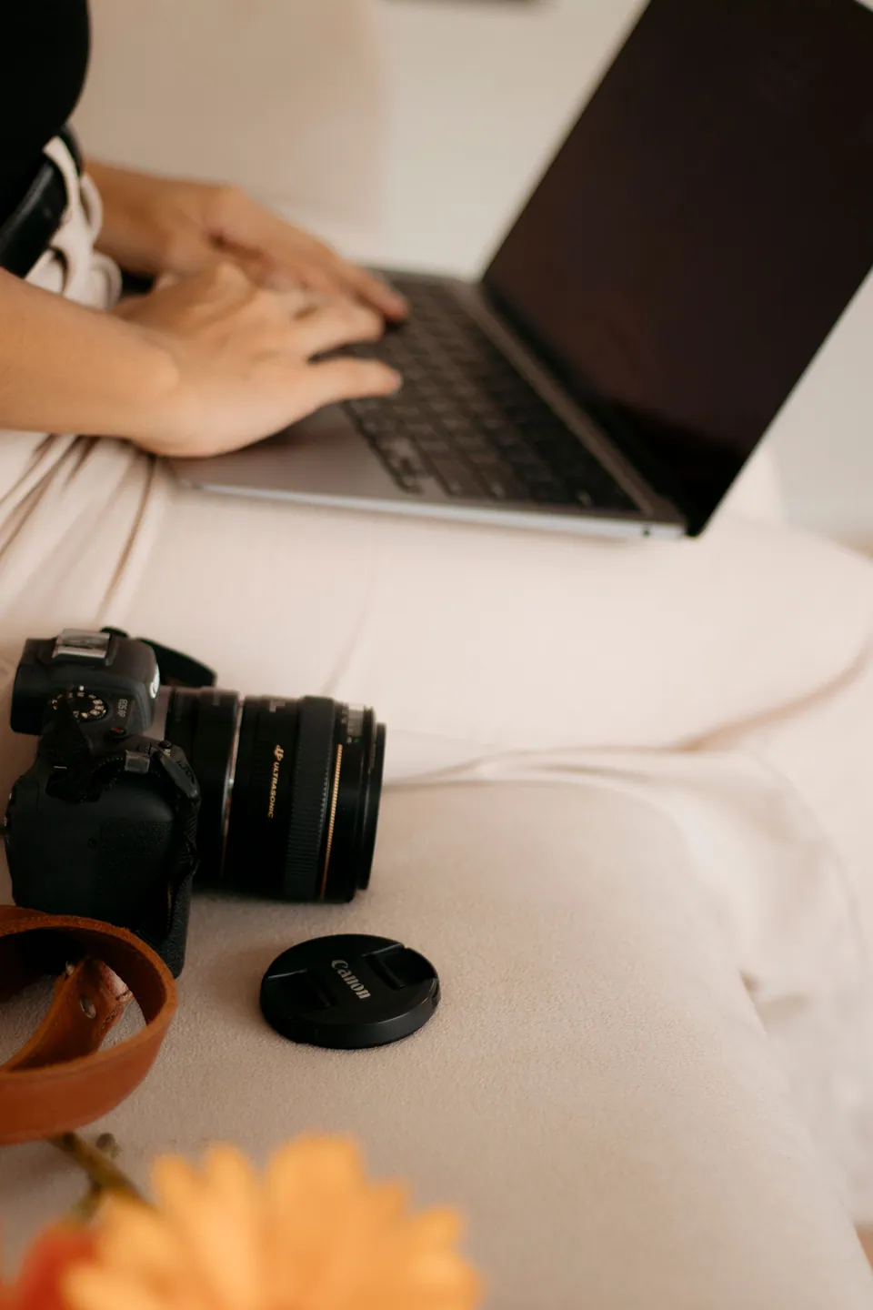 Photographer using a laptop with a camera resting nearby