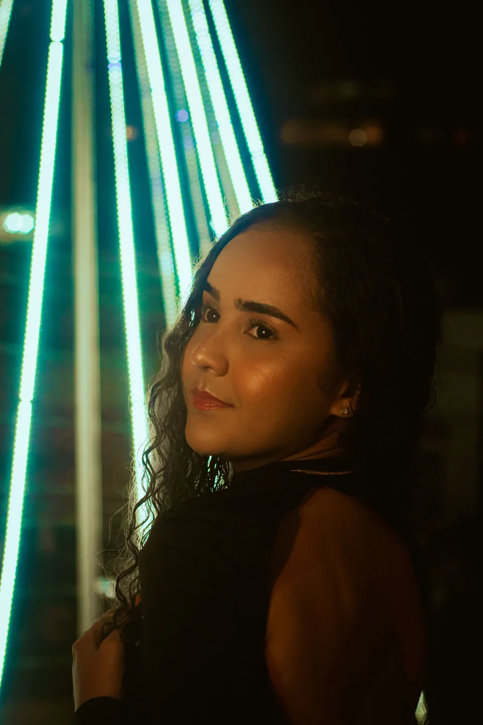 Portrait beside glowing turquoise lights at night