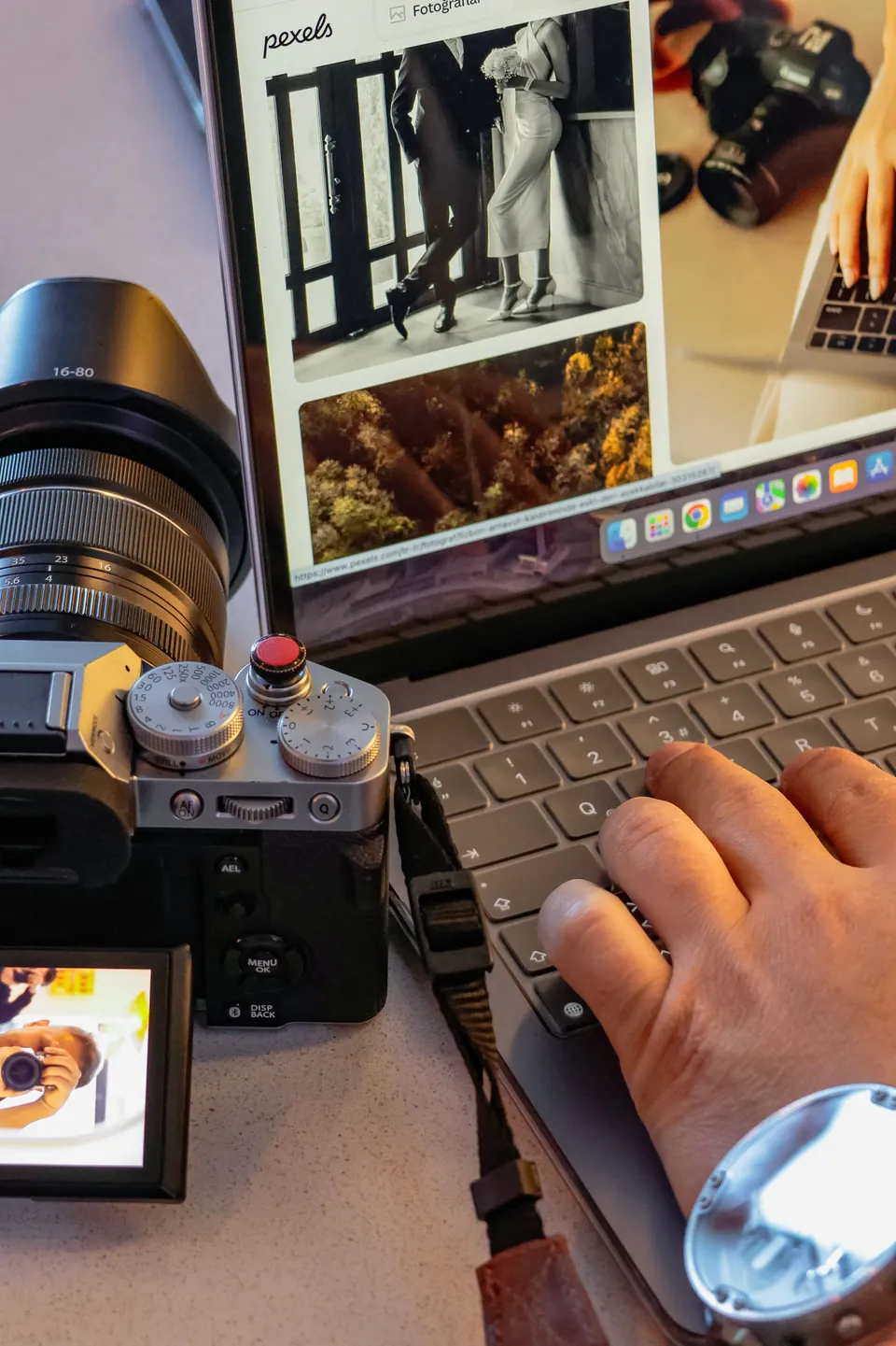 Camera beside a laptop displaying photographs for review