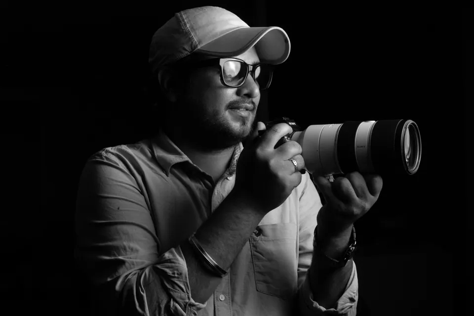Black-and-white portrait of a photographer holding a camera