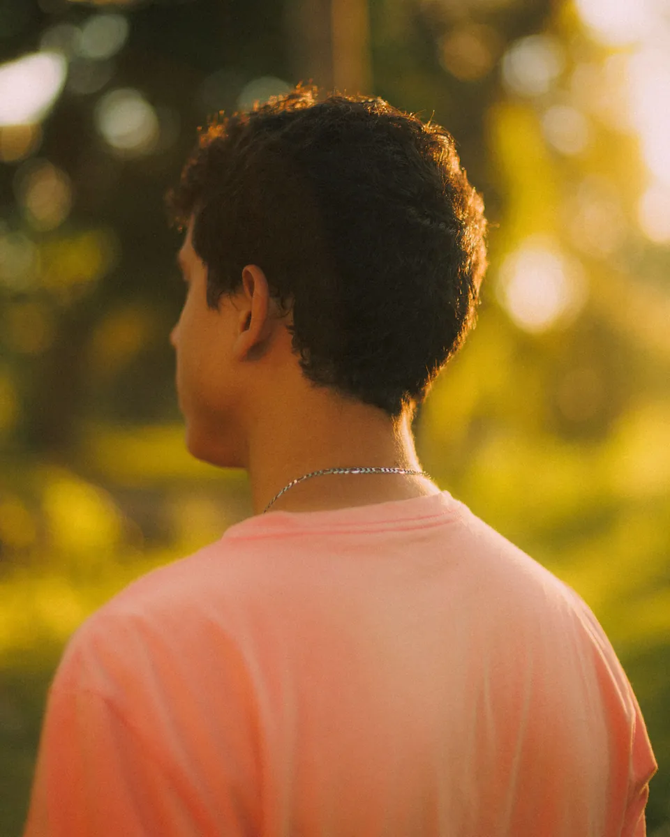 Man seen from behind with warm sunlight outlining his hair