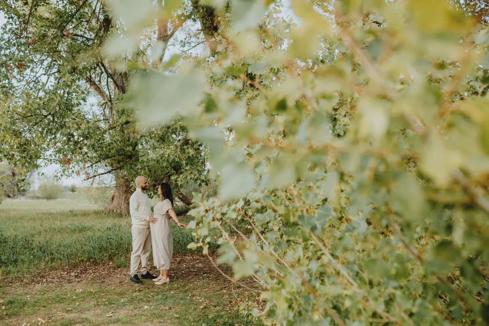 Couple standing together beneath leafy trees