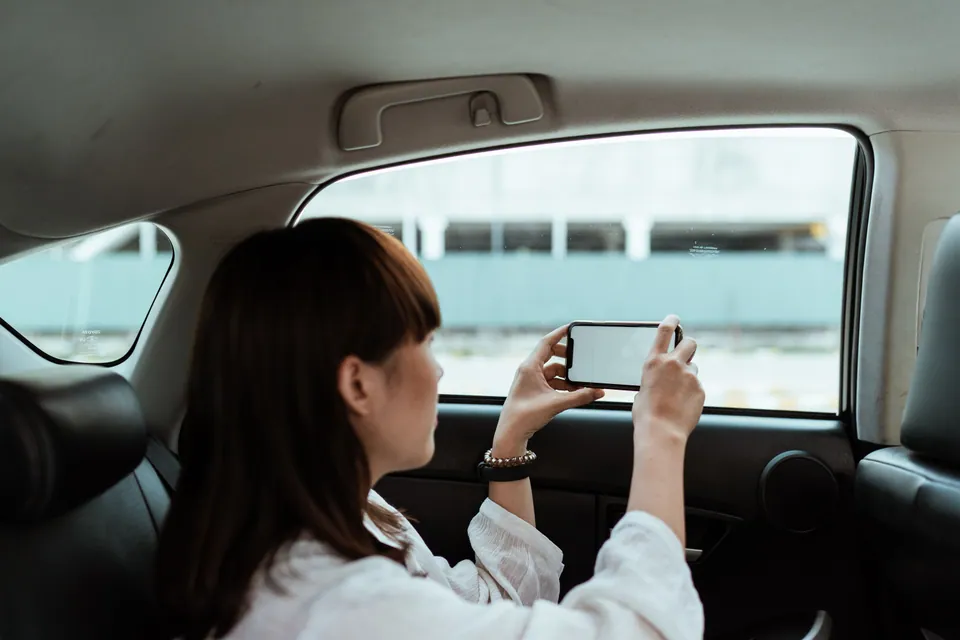 Passenger holding a smartphone beside a car window