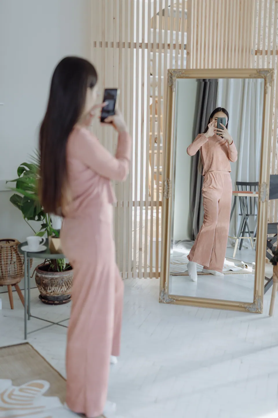 Woman taking a phone selfie in a full-length mirror