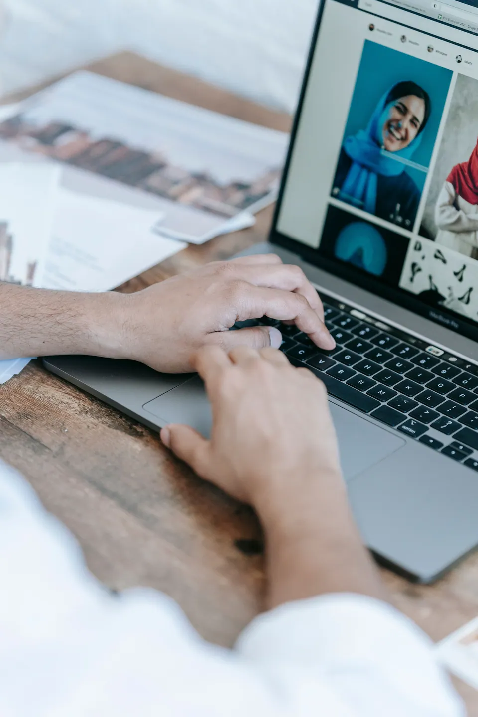 Hands at a laptop displaying a set of portrait photographs